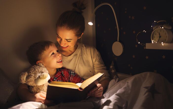 Cheerful mother and son cuddling and reading book